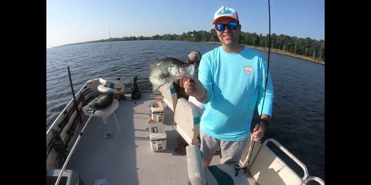 Angler holding fish on boat at lake