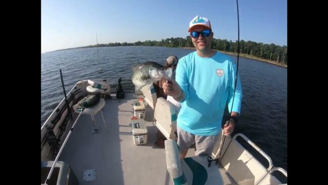Angler holding fish on boat at lake